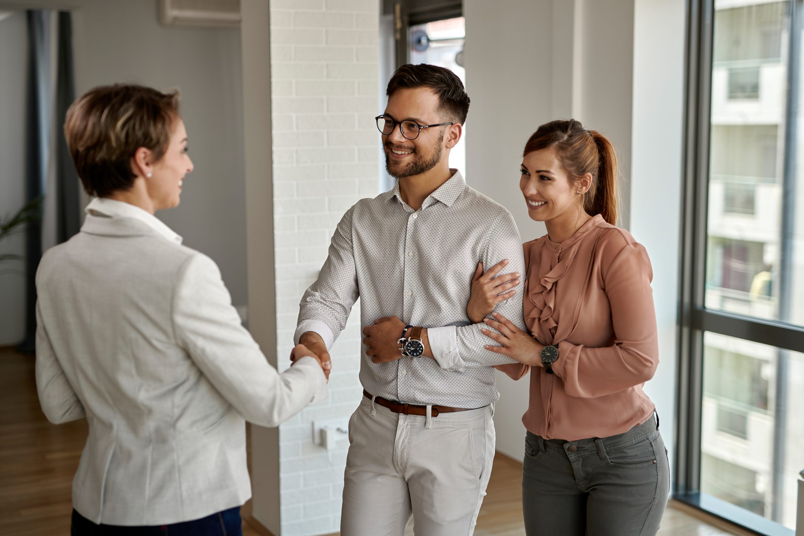 Happy couple greeting their real estate agent while buying a new
